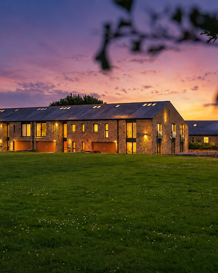 Stone property at twilight with warm interior lighting — JL Property Marketing