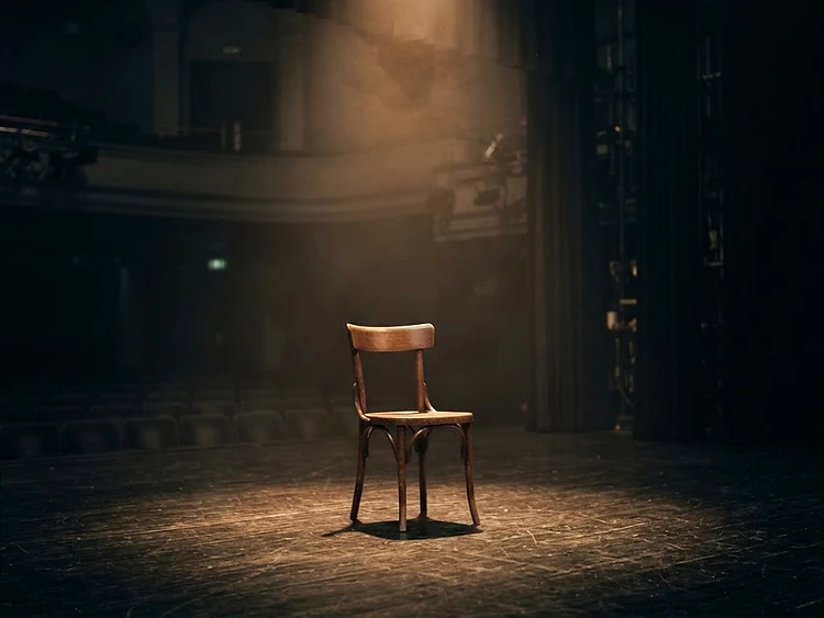 An empty stage lit by a single warm spotlight