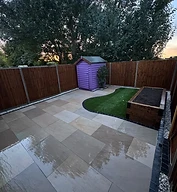 Finished porcelain patio with sleeper bed, turf island and fencing by CG Landscaping