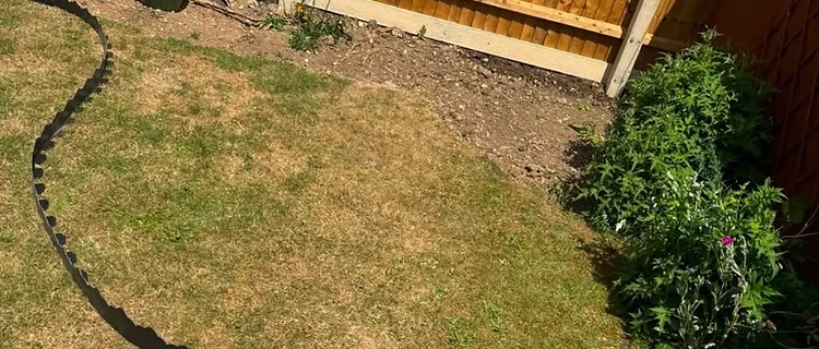 Garden before — curved black edging laid out on dry lawn ready for the new patio