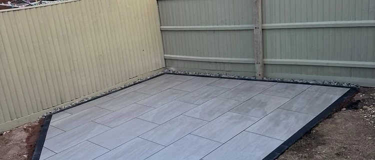 Finished pentagonal porcelain patio with charcoal block border by CG Landscaping
