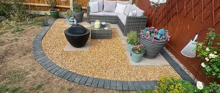 Completed porcelain patio with grey corner sofa, planter and water feature by CG Landscaping