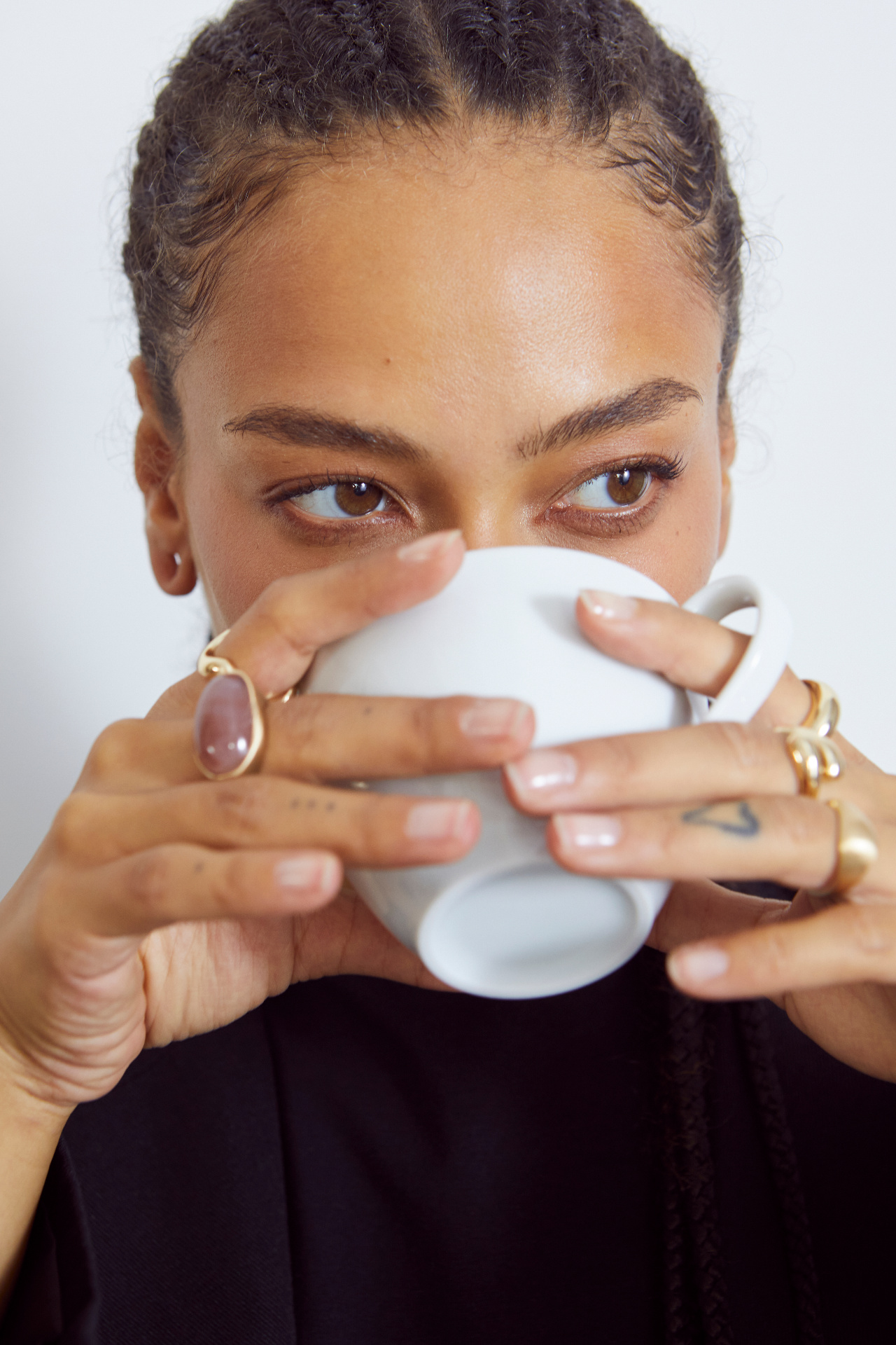 A woman mid-task, hands visible and incidental: typing, holding a coffee, signing something.