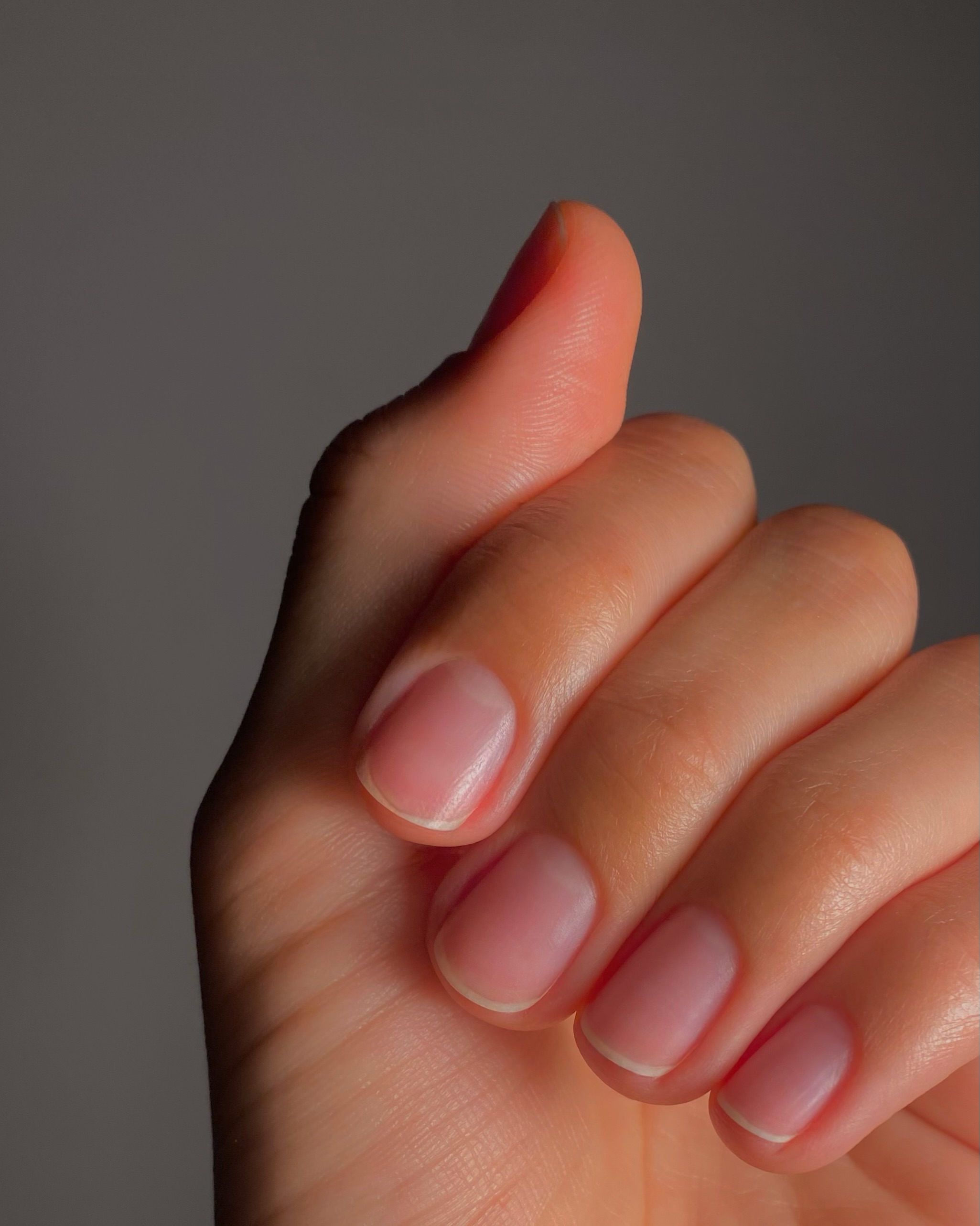 Short bare natural nails, rings, a sweater sleeve.