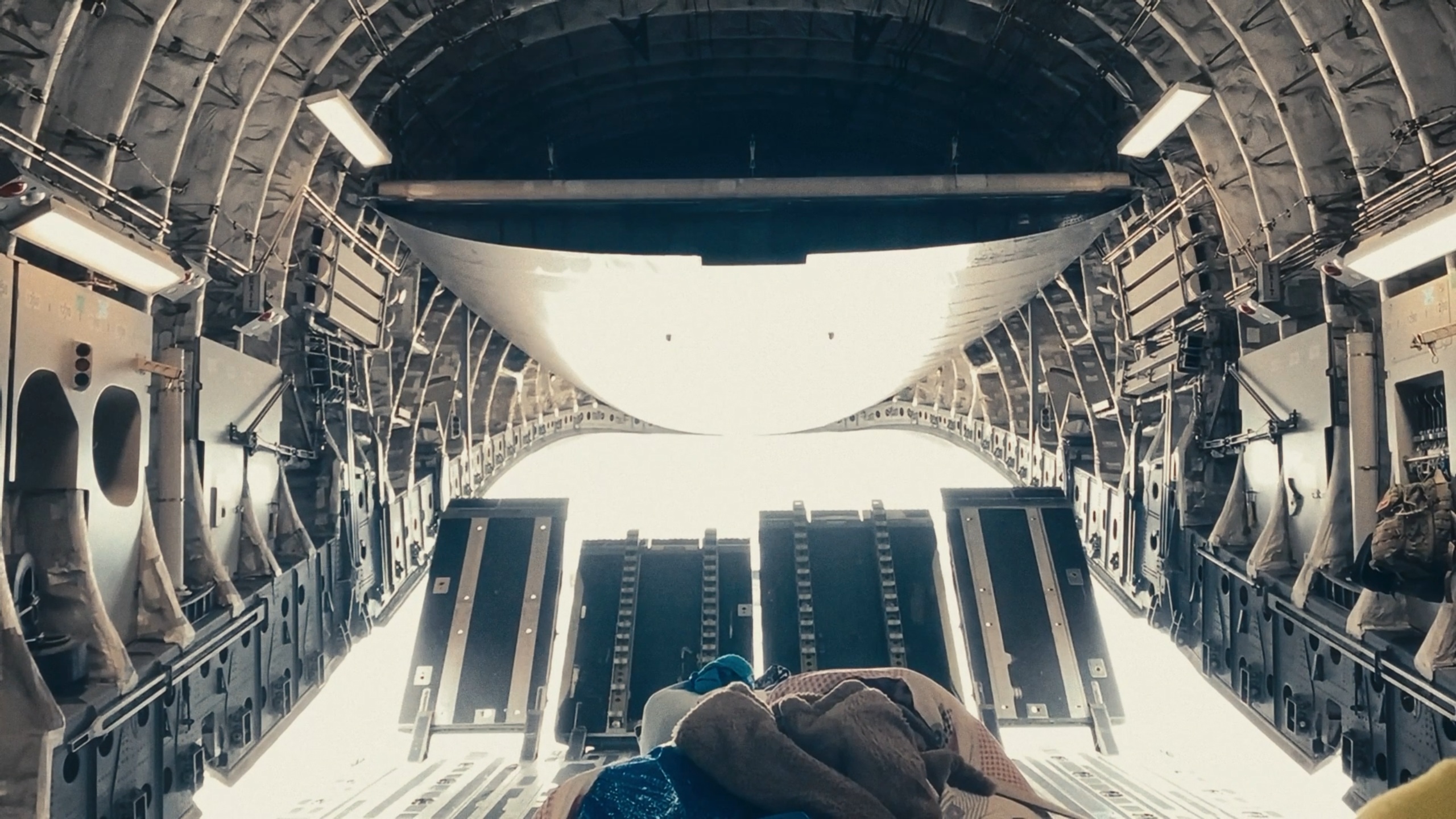 Inside a military cargo aircraft, the rear ramp opens to blinding light