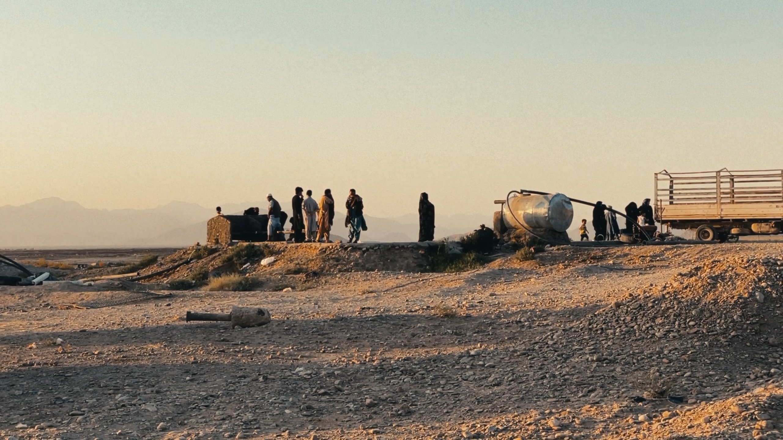 A line of silhouetted figures stands on a desert ridge at golden hour