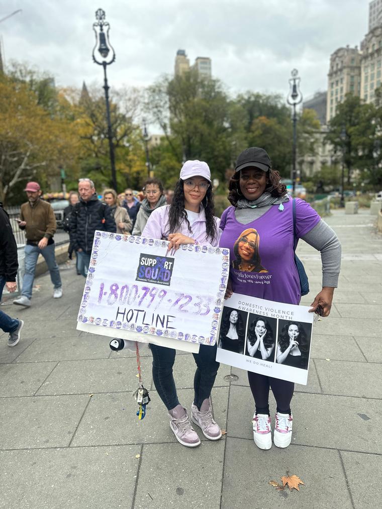 At a domestic violence awareness walk holding signs, one with the hotline number