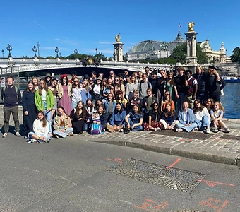 Denoxa Adventures group photo of students on the banks of the Seine with a Parisian bridge behind them