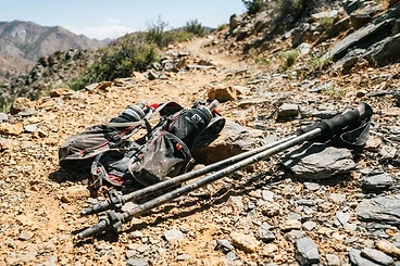 Hydration vest and trail poles on rocky ground