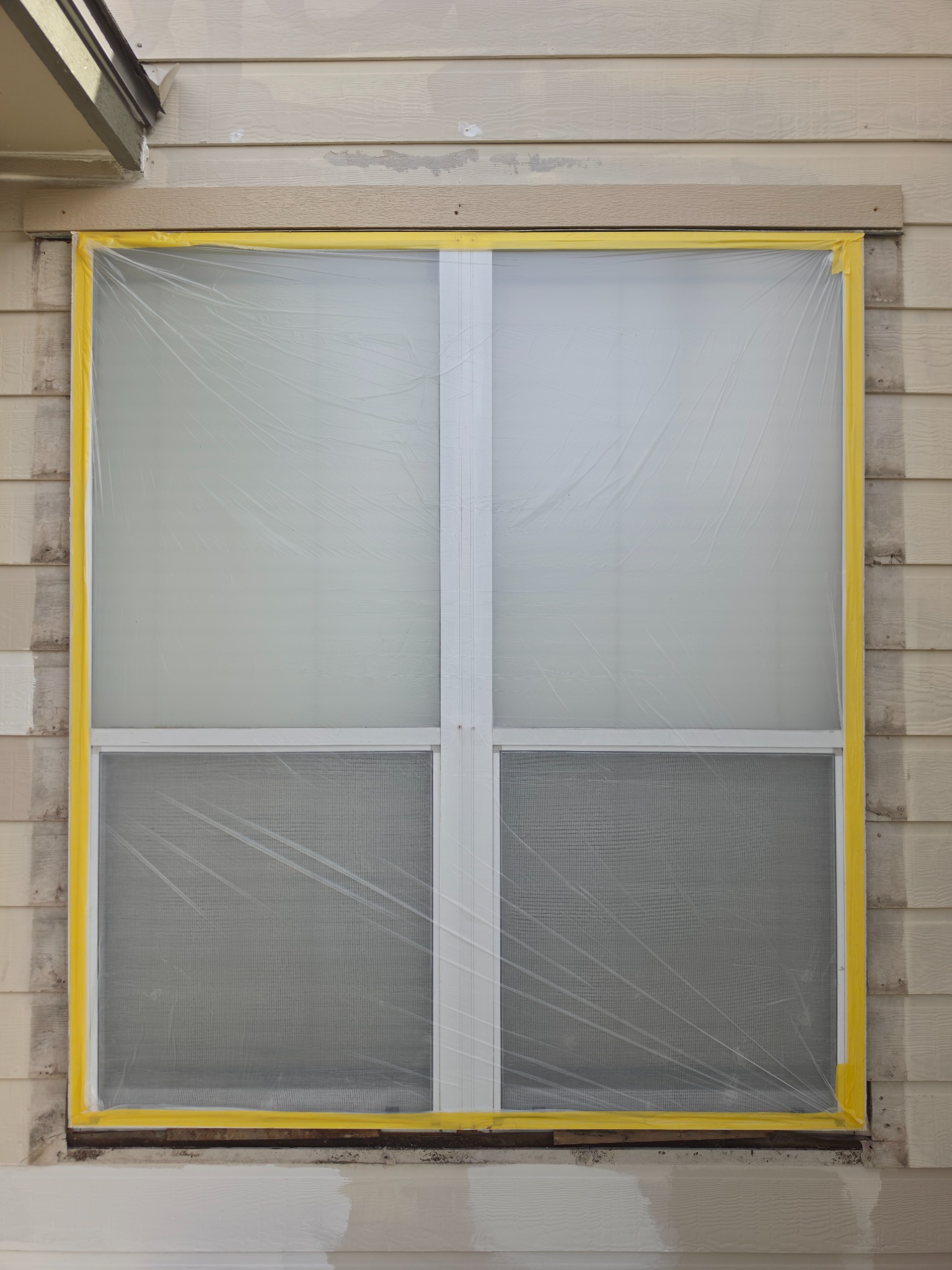 Window trim masked and prepared before exterior painting.