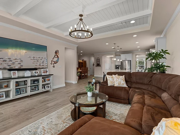 Finished living room with a detailed white coffered ceiling, painted walls and built-in cabinetry