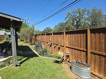 Weathered wood fence running along a backyard patio before washing