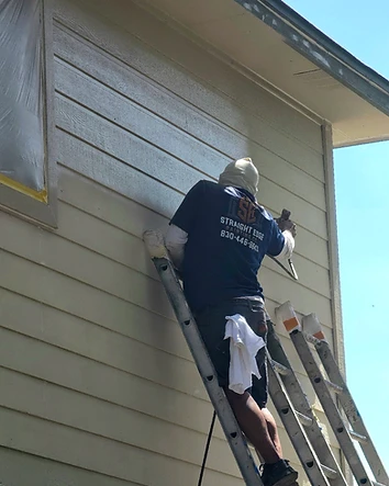 Straight Edge Painting Company crew member spraying exterior siding in San Antonio, Texas.