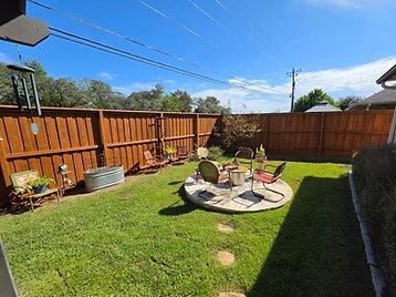 Stained wood fence surrounding a backyard with a circular stone seating area and a fire pit