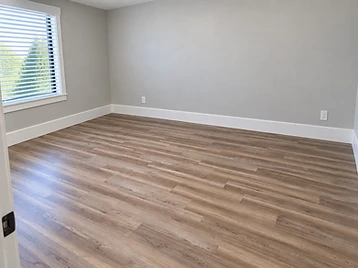 Bedroom after new plank flooring and white baseboard installation
