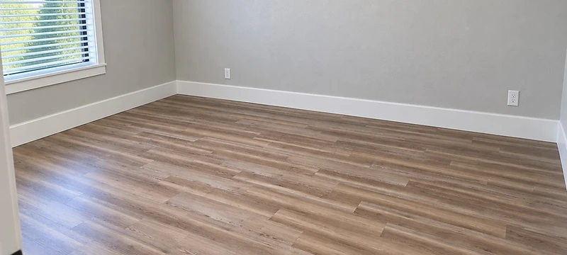 Bedroom after new plank flooring and white baseboard installation