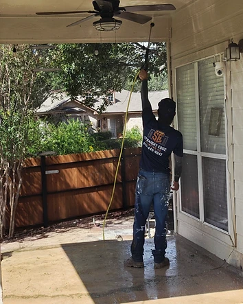 Straight Edge Painting Company crew member pressure washing a covered patio in San Antonio, Texas.