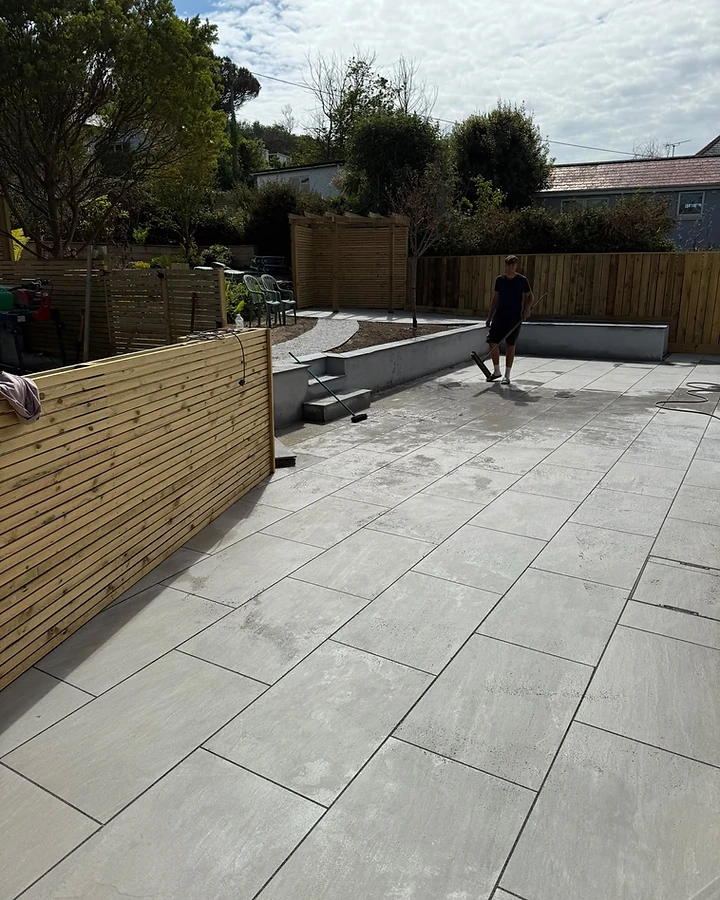Stone-effect paving laid in stretcher bond with rendered retaining wall and timber screening