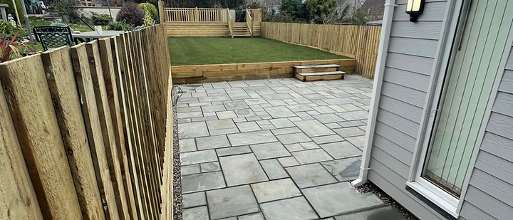 Landscaped garden with stone patio and timber sleeper retaining walls in Cornwall