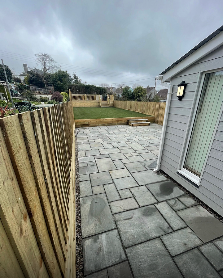 Grey stone patio with lawn, fencing and sleeper borders