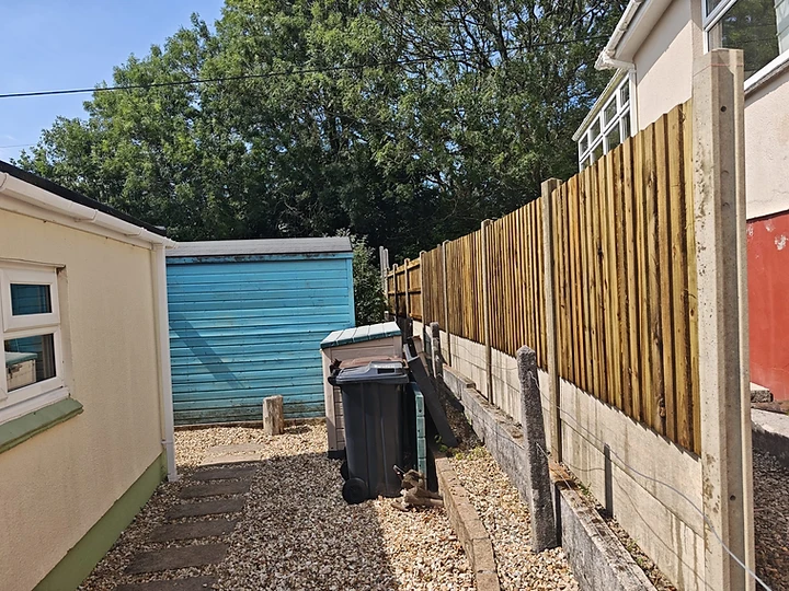 Side alley with gravel, stepping stones and timber fencing on a low wall