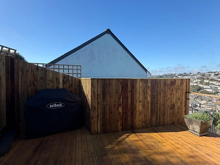 Stained timber decking with vertical fence and outdoor grill