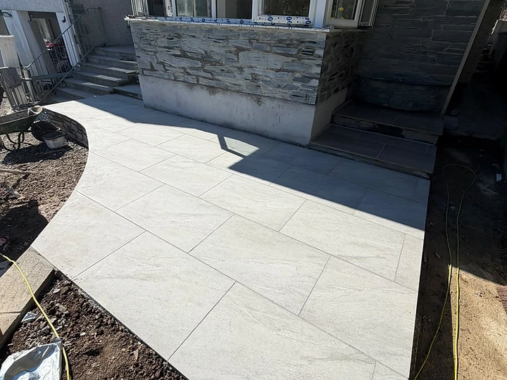 Newly laid stone-effect patio with natural stone cladding beneath a bay window