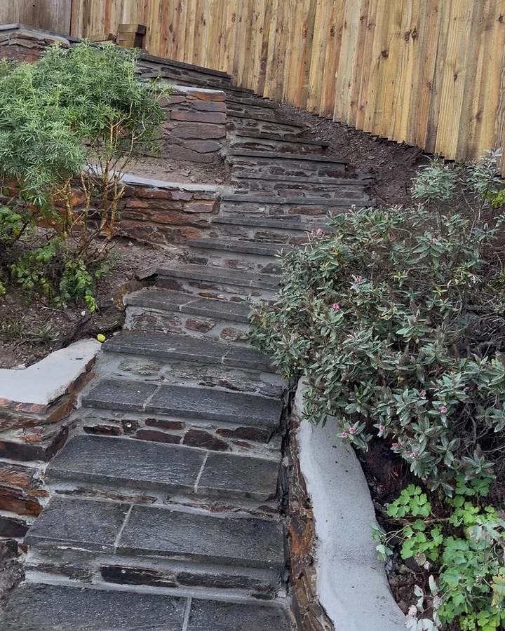 Curved stone garden staircase with rendered retaining walls and capped wall