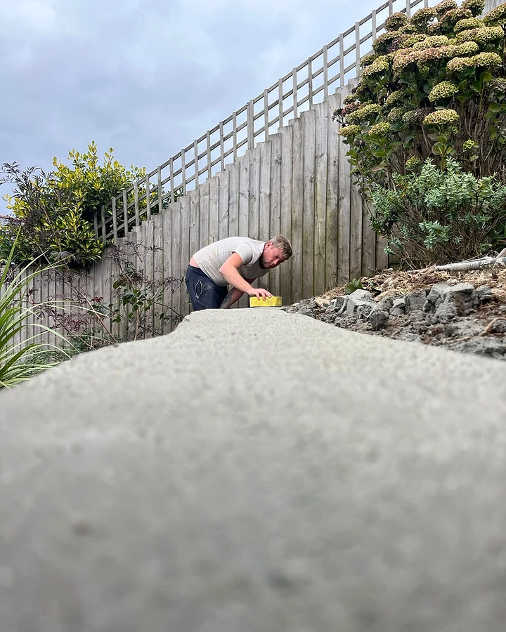 Worker finishing a curved concrete retaining wall border with a float