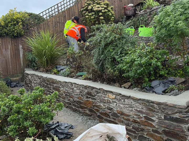 Tiered garden retaining wall under construction with stone and concrete coping