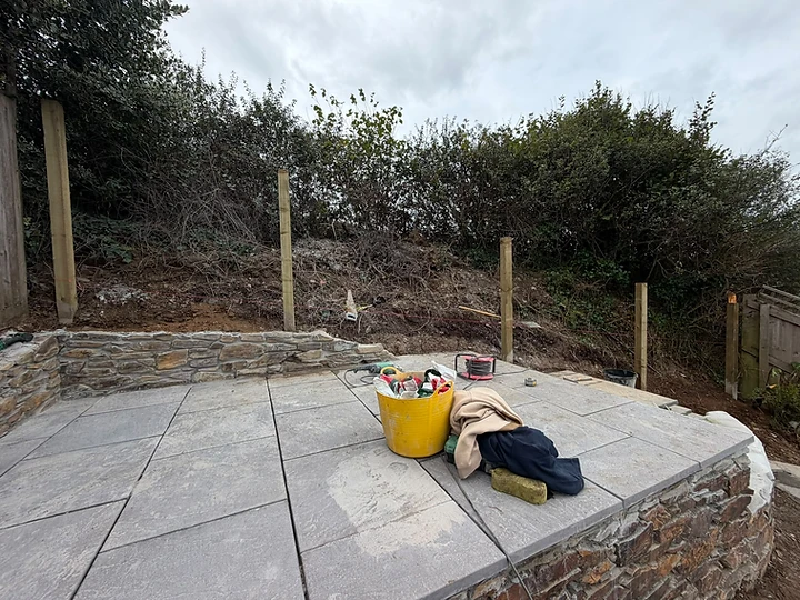 Stone paving laid with dry-stone retaining walls and fence posts set to a string line