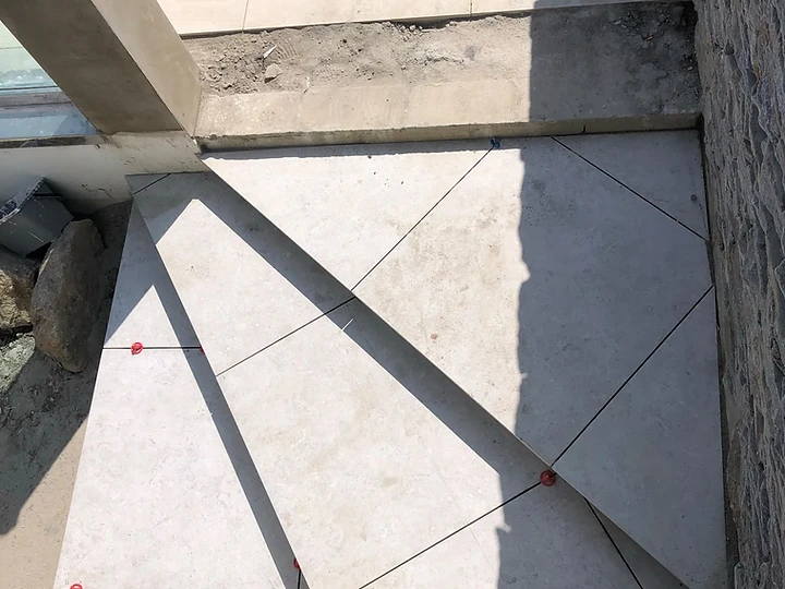 Large-format patio tiles being laid with leveling clips in geometric pattern