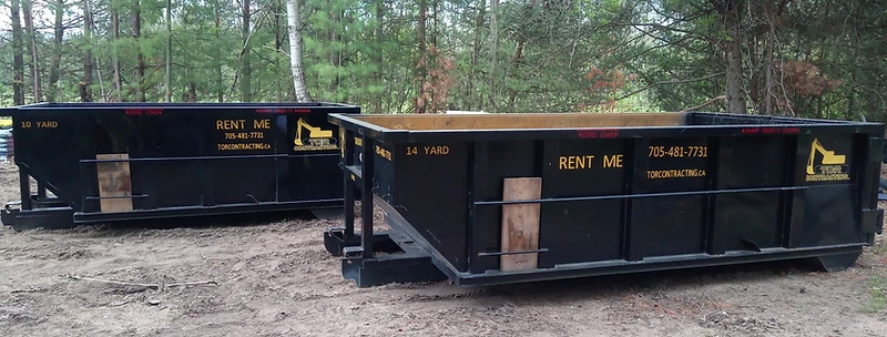 Two Tor Contracting roll-off bins with a forest backdrop