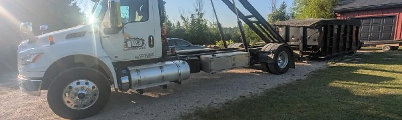 Tor Contracting hook-lift truck lowering a roll-off bin