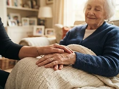 A caregiver's hand gently resting on an elder's hand