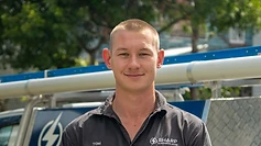 Tom, a Sharp Electrical & Air team member, in branded work uniform in front of the company service vehicle