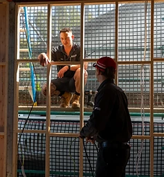 Two electricians wiring a timber frame wall during a new home construction