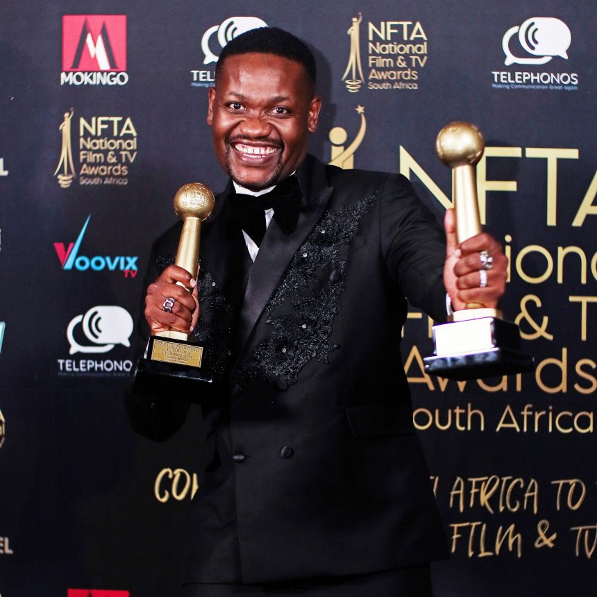 Clement Maosa holding two golden trophies at the NFTA South Africa red carpet