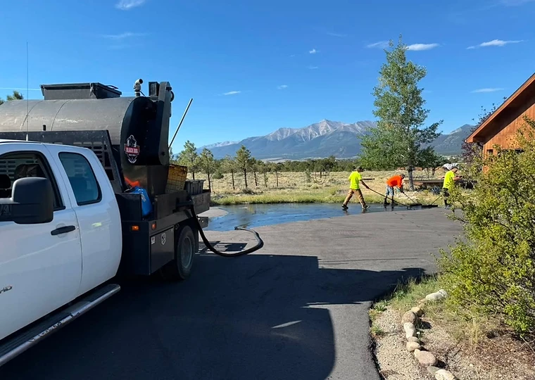 Black Dog Asphalt Services crew applying seal coat to a residential driveway with squeegees