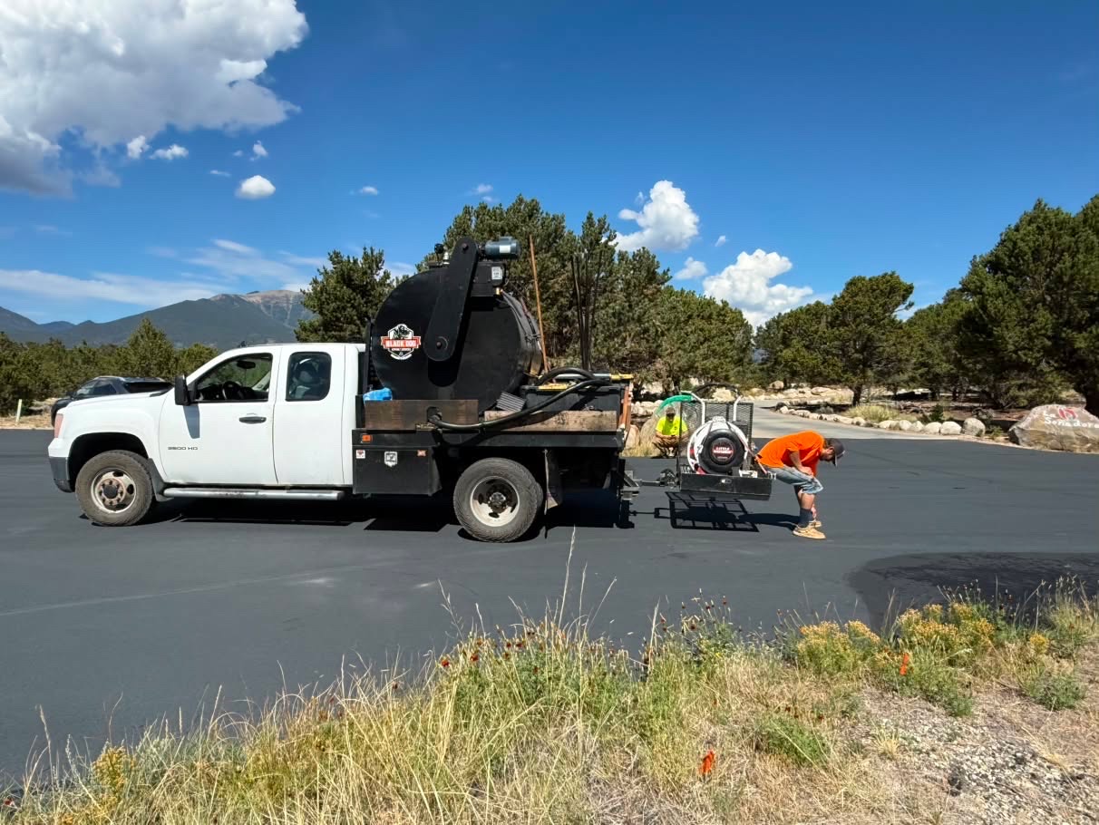 Black Dog Asphalt Services branded truck with sealcoating tank on site