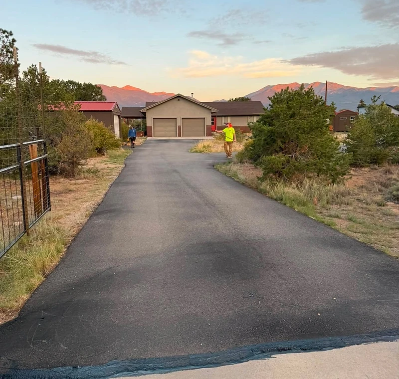Freshly seal-coated residential asphalt driveway at twilight with alpenglow on the mountains near Buena Vista Colorado
