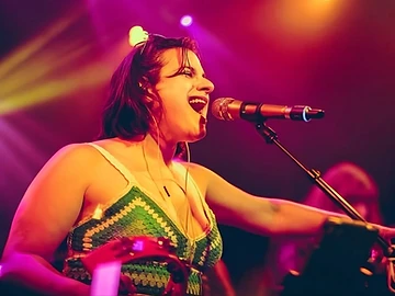 Liz Ashkins on stage — pink and yellow stage lighting
