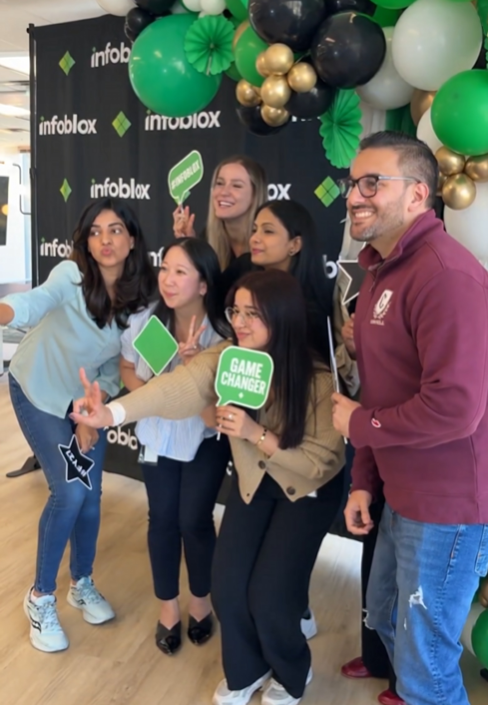Infoblox team posing at a QuickPic open-air photo booth with a branded backdrop and balloon arch