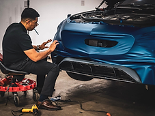 Technician applying matte blue vinyl to a bumper