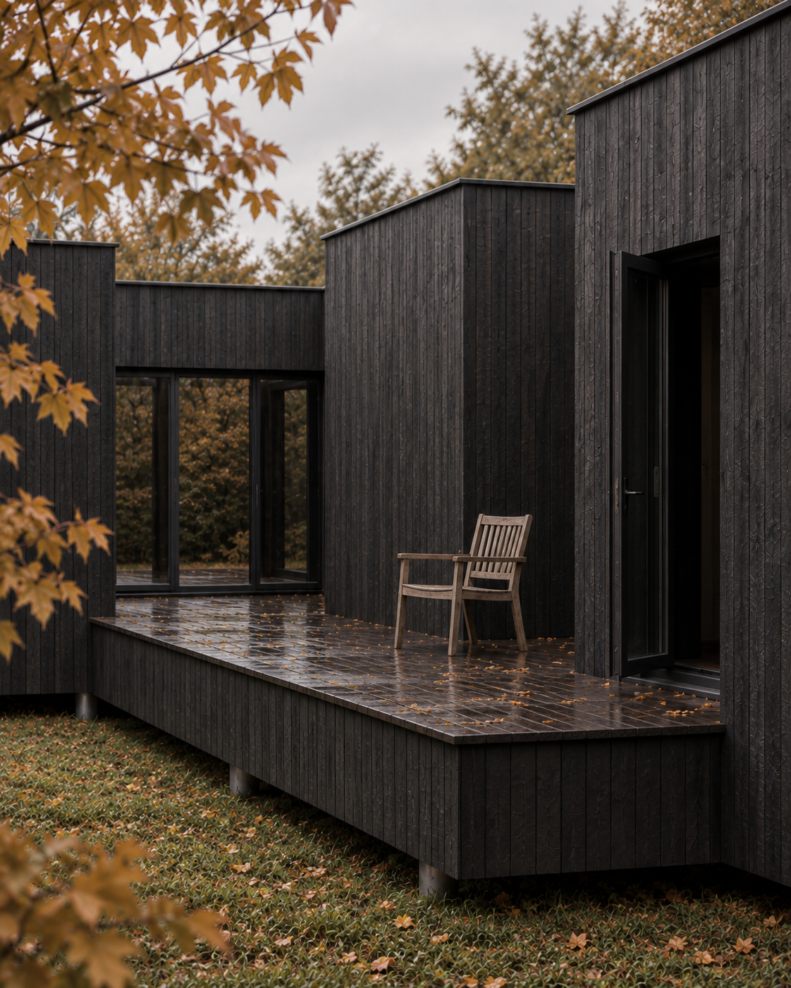Maison en bois brûlé, terrasse et fauteuil en bois clair