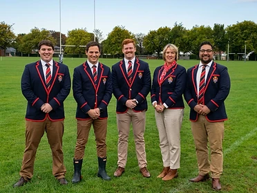 A university rugby team wearing matching custom navy blazers with red piping and embroidered crests on a rugby pitch.