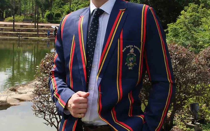 Man wearing a navy military blazer with red and yellow stripes and a Royal Marines Association crest