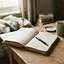 An open notebook with hand ruled columns and a pen resting on it
