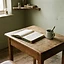 A small desk with a ruled ledger book, a cup and a pen