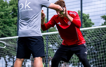 Trainer demonstriert Ballkontrolle mit grünen Trainingsbällen